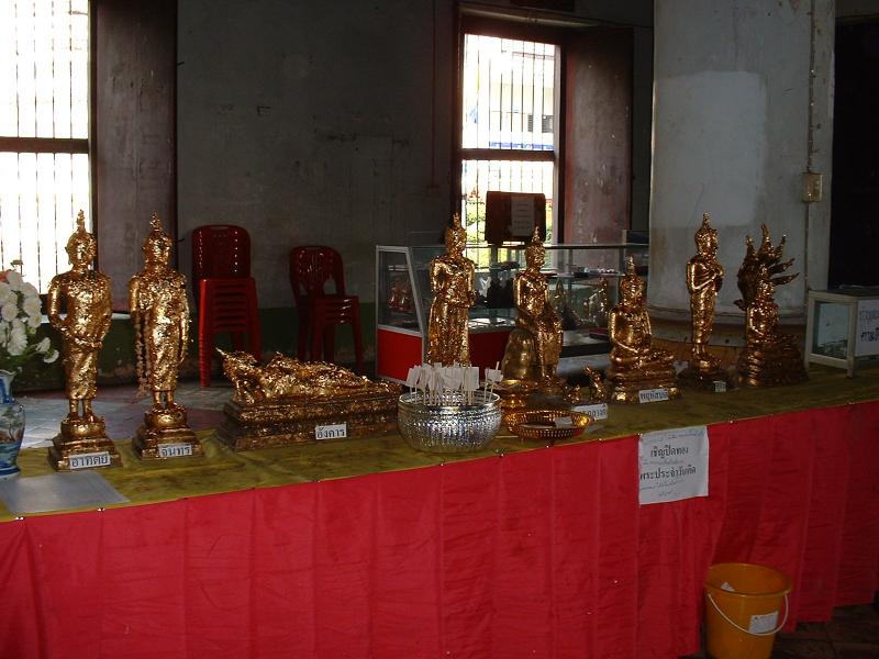 Huit statuettes représentant les huit positions de Bouddha et sur lesquelles les gens viennent coller des feuilles d'or